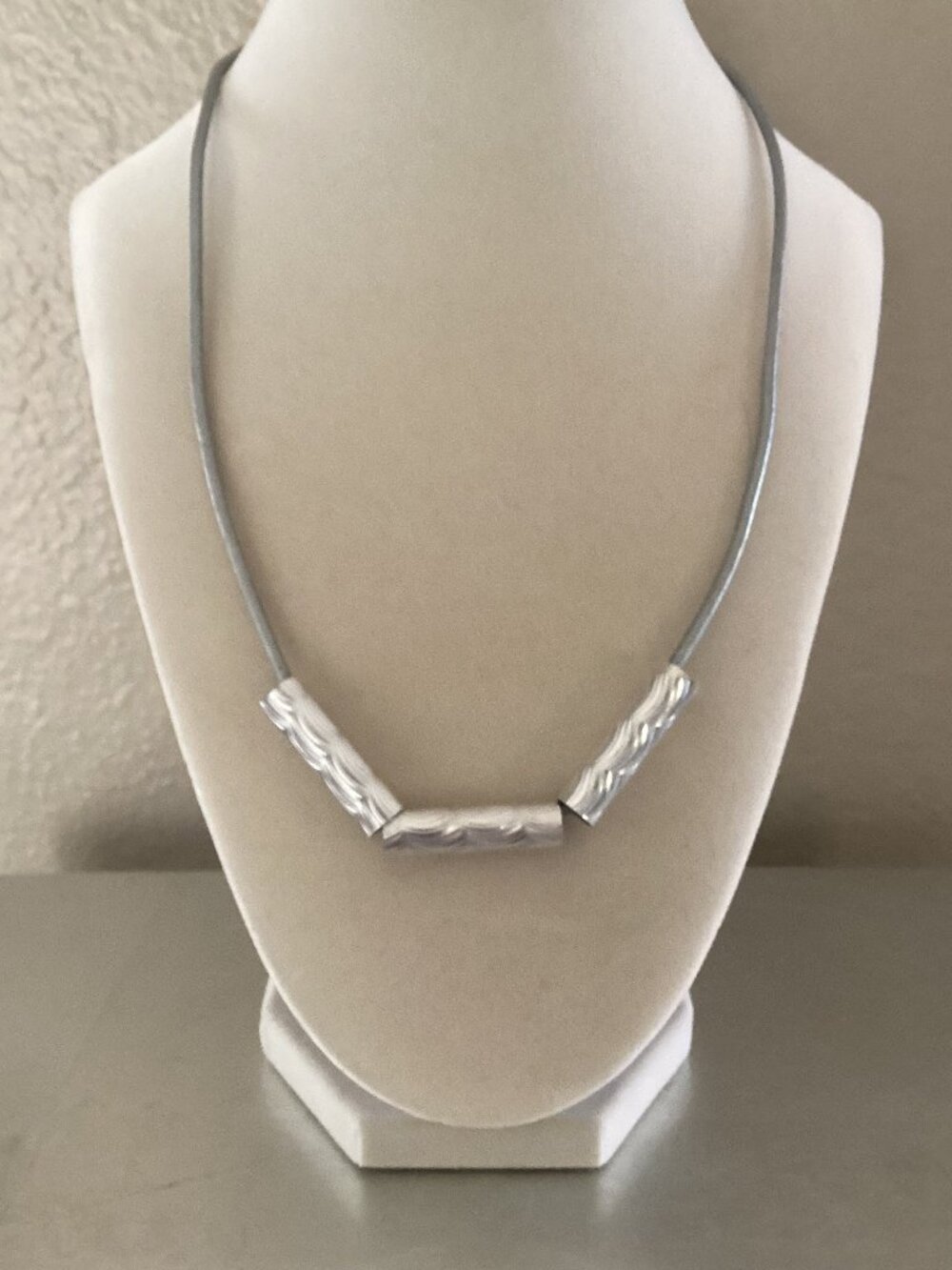 Silver beaded necklace on gray cord with lobster clasp, 19 inches.
